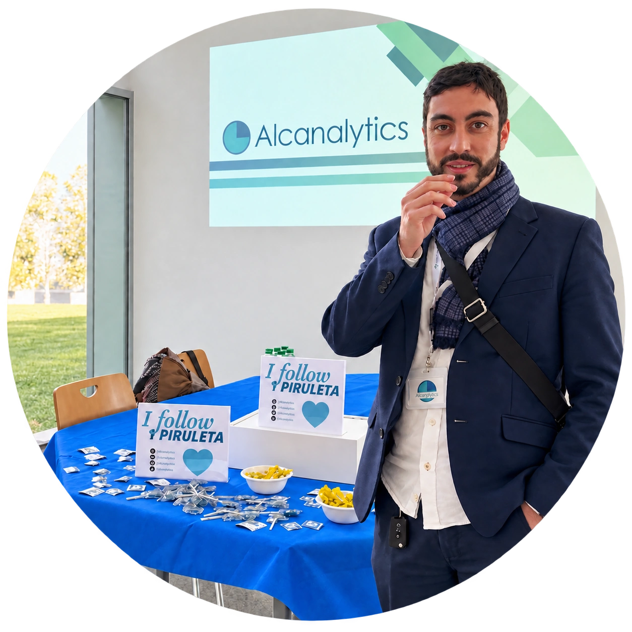 Profesional junto a una mesa promocional y una proyección de Alcanalytics en un evento